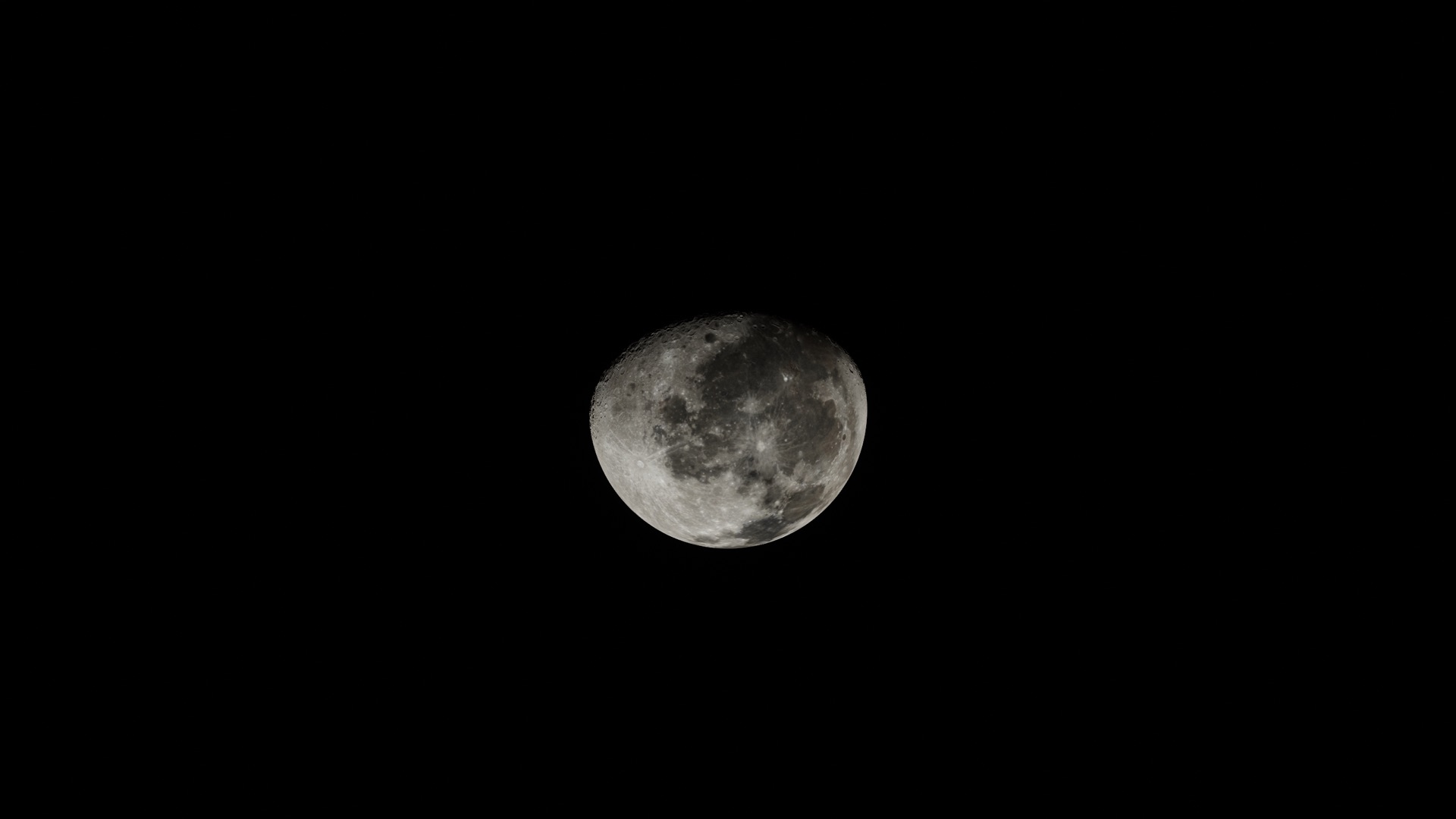 The Moon, nearly full, alone in black space, as seen from the ship on its way.